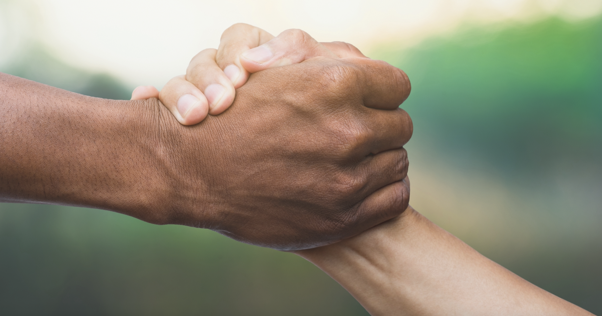 A close-up image of two people grasping hands in support