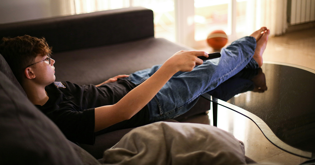 Young adult watching TV on the couch