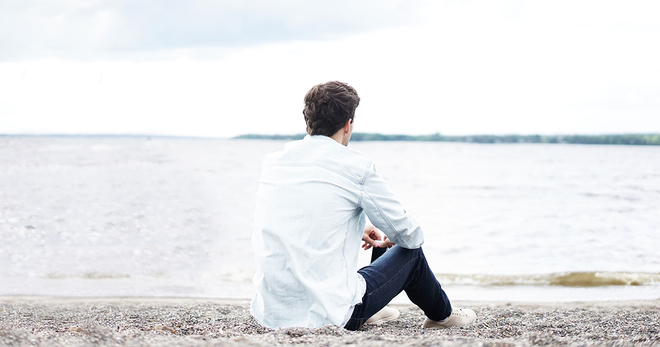 Young adult sitting alone on a beach